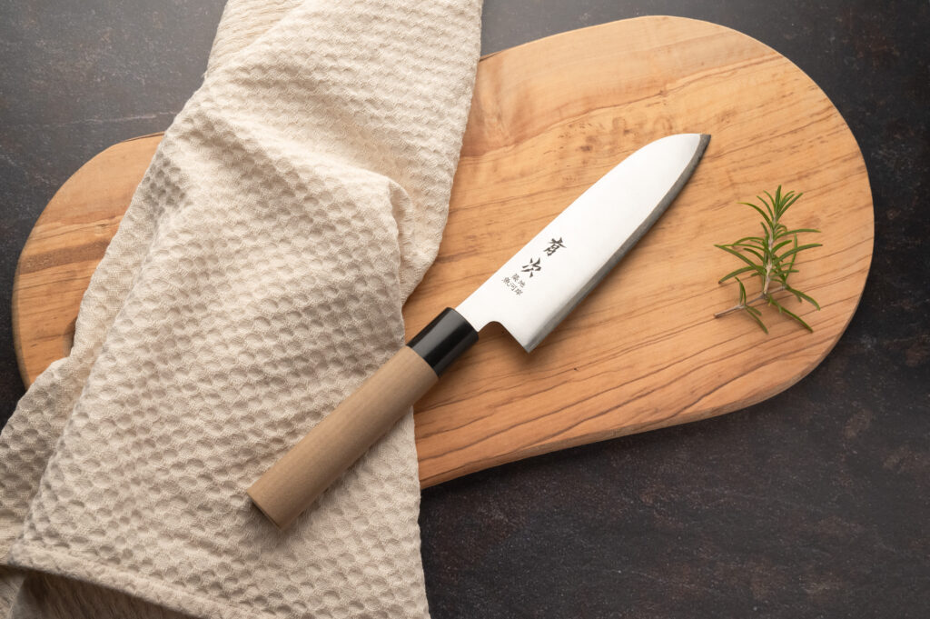 Produktfotografie: Japanisches Messer auf Holzbrett mit Geschirrtuch links